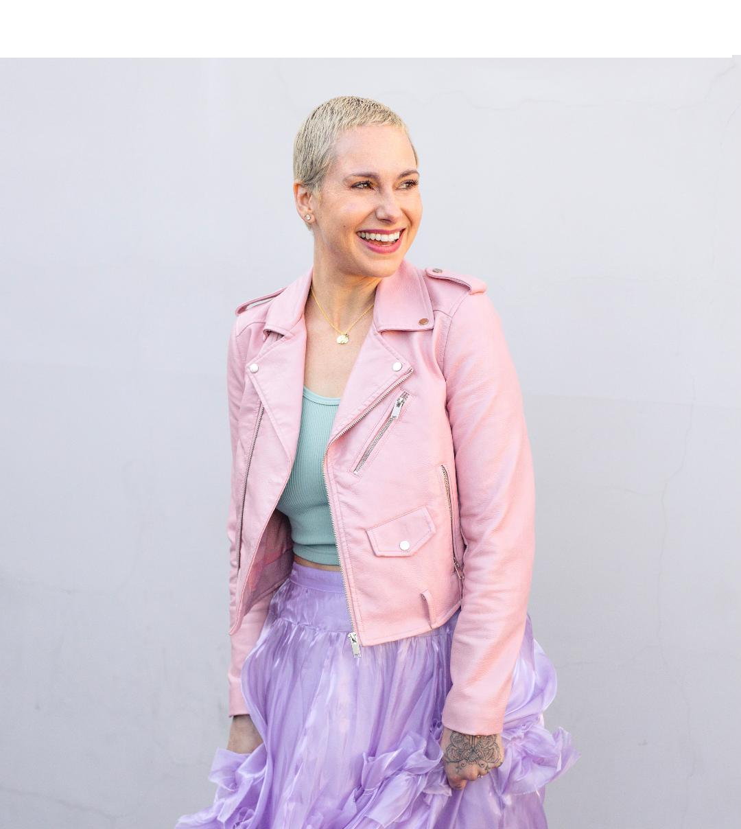 Image shows Faith Streng wearing a purple skirt, mint green top and pink jacket. She is smiling.