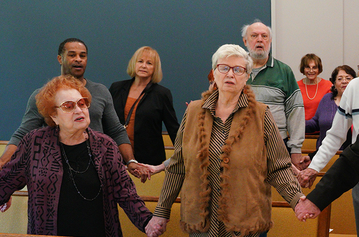 Image shows members of the congregation holding hands and singing.